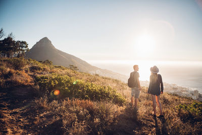 Rear view of people walking on mountain against sky