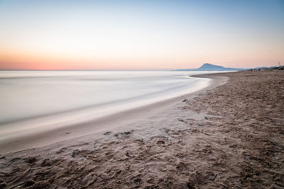 Scenic view of beach against clear sky during sunset