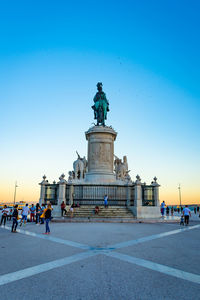 Statue in square against clear blue sky with peopke