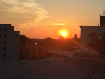 Houses in city against sky during sunset