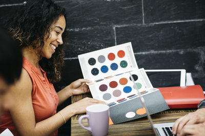 Smiling young woman holding color swatch in creative office
