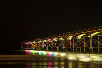 Illuminated bridge over river in city at night