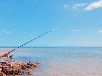 Fishing rod over sea against sky
