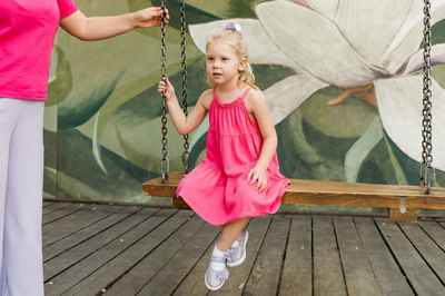 Low angle view of young woman swinging at park