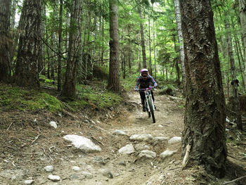 Full length of man riding bicycle in forest