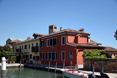 View of buildings by canal against clear blue sky