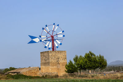 Low angle view of windmill against clear blue sky