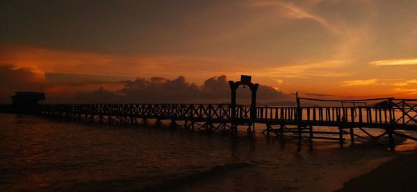 Pier over sea against sky during sunset