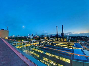 High angle view of illuminated city against blue sky