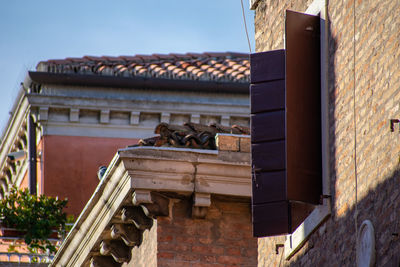 Low angle view of old window and tile roof of building