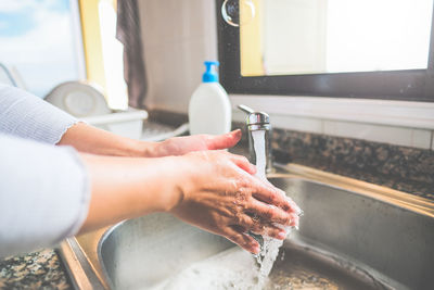 Cropped image of person washing hand in sink