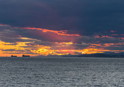 Scenic view of sea against dramatic sky during sunset