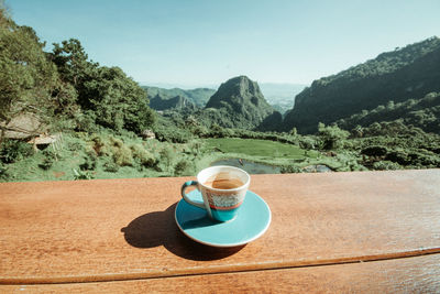 Coffee cup on table against mountain