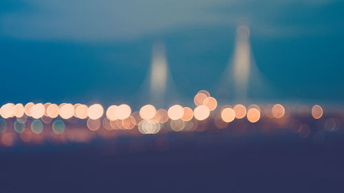 Defocused image of illuminated lights against sky at night