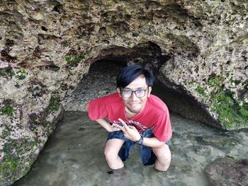 Portrait of smiling young man standing on rock