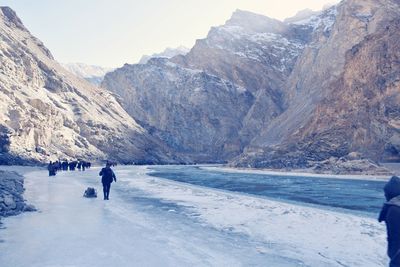 Rear view of woman walking on snowcapped mountain