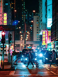 Cars on city street by buildings at night