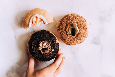 Cropped hand of person holding donut on table