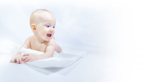 Portrait of cute baby boy sitting against white background