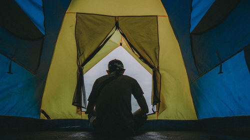 Rear view of man sitting at tent