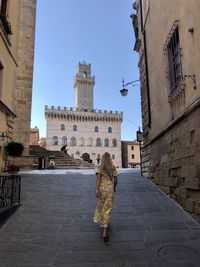 Rear view of women walking on historic building in city