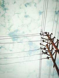 Low angle view of birds perching on electricity pylon against sky