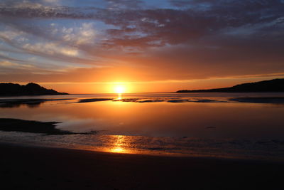 Scenic view of sea against dramatic sky during sunset