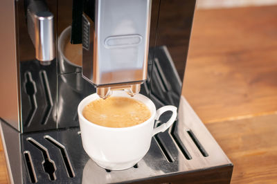 Espresso pouring from coffee machine, close up, professional coffee brewing.