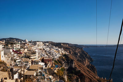 High angle view of townscape by sea against clear blue sky