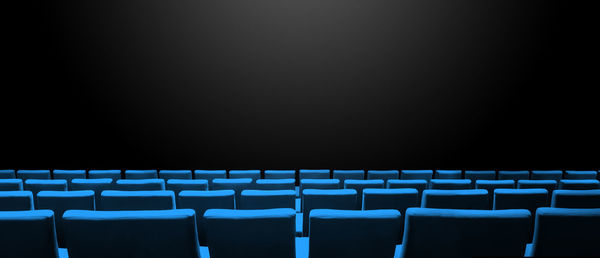 Empty chairs in row against black background