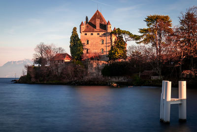 Building by lake against sky