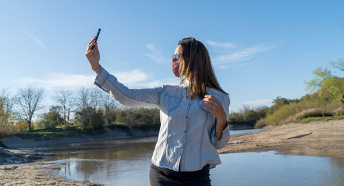 Man standing on mobile phone against sky