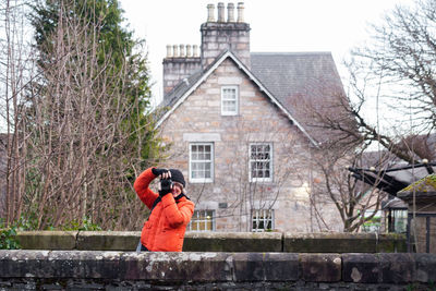 Man photographing against building
