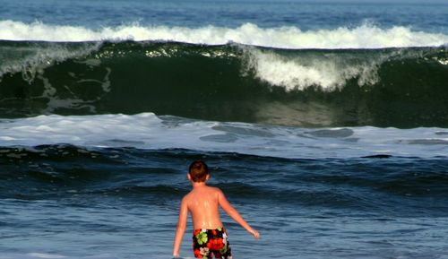 Rear view of boy standing in sea