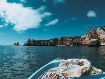 Man relaxing on rocks by sea against sky