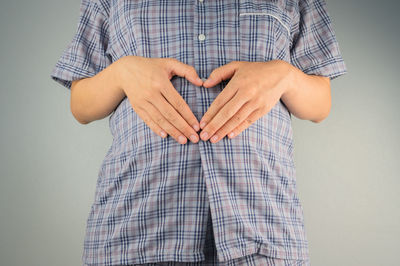 Midsection of man holding heart shape against white background