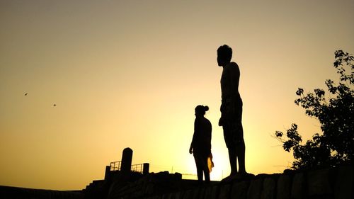 Silhouette men standing against clear sky during sunset