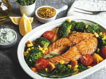 Roast, fried, baked fish steak salmon, trout with broccoli, carrots, tomato in ceramic baking dish, 