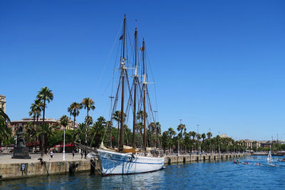 Sailboats moored at harbor against clear blue sky