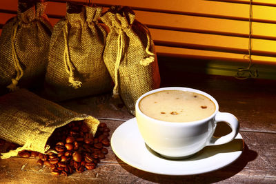 Coffee cup filled with coffee set against a kitchen window blind 