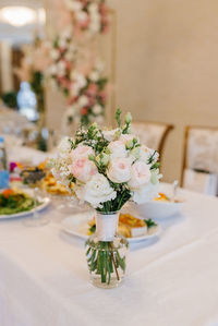 A delicate bridal bouquet of the bride stands in a glass vase on a festive banquet table