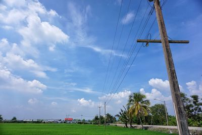 Low angle view of electricity pylon on field against sky
