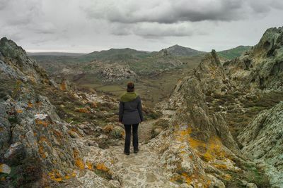 Rear view of woman standing on mountain against sky