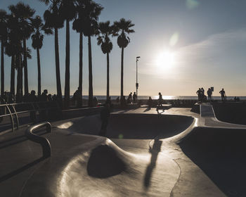 People in skateboard park against sea and sky during sunset