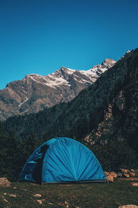 Tent in mountains against clear blue sky