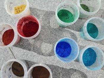 High angle view of colorful powder paints in containers on walkway