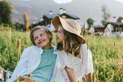 Siblings sitting on field