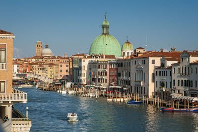 Canal amidst buildings in city against clear sky