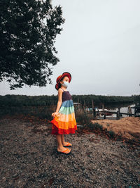 A little girl in a rainbow dress stands at the jetty. summer day.