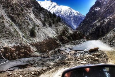 Snow covered road by mountains against sky